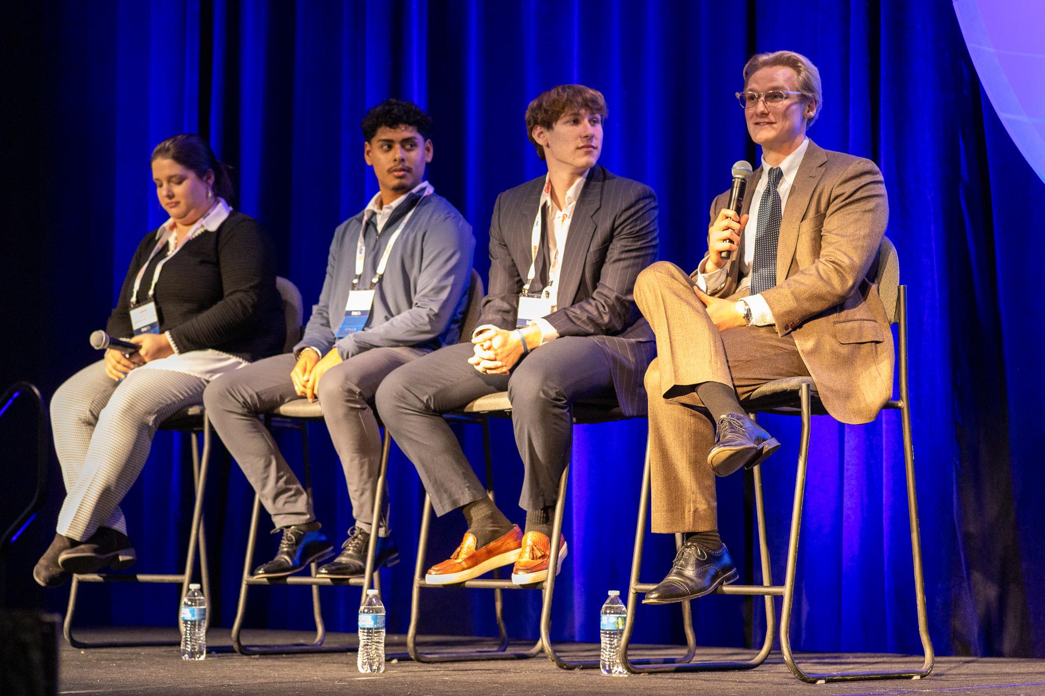 Image of 4 students on stage, one is speaking